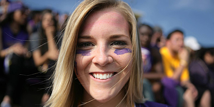 Close up of person smiling with purple streak on their cheeks 