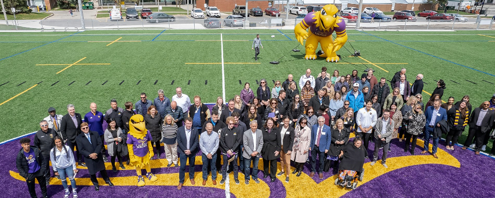 Group of people standing on the new alumni field 