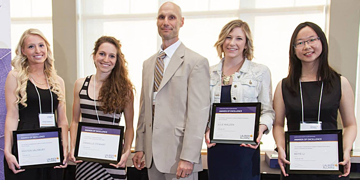 Group of people smiling with framed certificates 